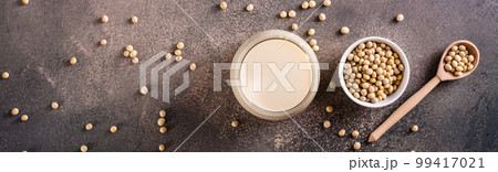 Glass of soy milk and soy beans on the table. Vegetable protein. Top view. Web banner 99417021