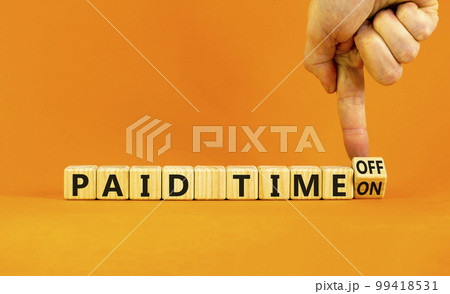 Paid time off or on symbol. Businessman turns a wooden cube and changes words 'paid time on' to 'paid time off'. Beautiful orange background. Business and paid time off or on concept, copy space. 99418531
