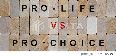 Wooden blocks form the words 'pro-life vs. pro-choice'. Beautiful wooden background. Female right on abortion concept, copy space. 99418539