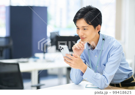 オフィスで働くスマホを持った私服の若い男性ビジネスマン 99418625