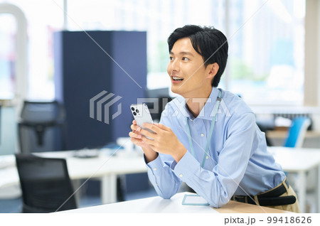 オフィスで働くスマホを持った私服の若い男性ビジネスマン 99418626
