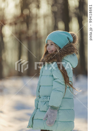 girl in a turquoise squat and a hat in the winter forest girl in a turquoise squat and a hat in the winter forest 99418661