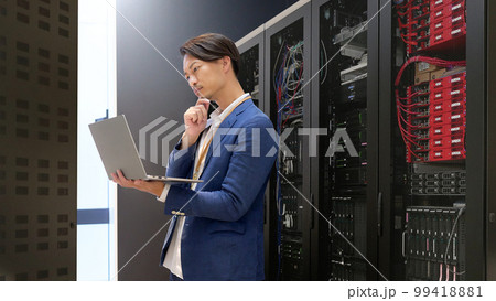 サーバールームでコンピューターをチェックする情報システム担当者　情シス　ビジネスイメージ 99418881