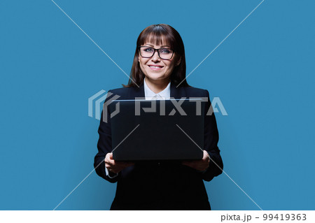 Mature business woman posing with laptop on blue studio background Mature business woman posing with laptop on blue studio background 99419363