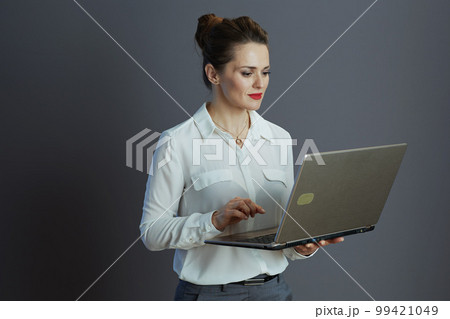 40 years old woman employee using laptop isolated on grey 99421049