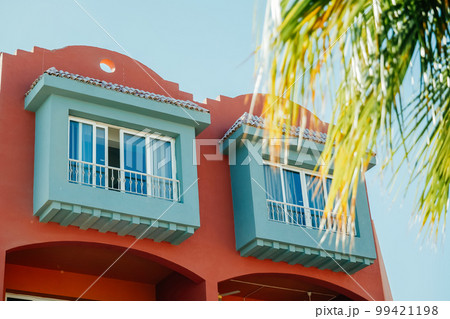 Colourful red house with blue balcony against blue sky Colourful red house with blue balcony against blue sky 99421198