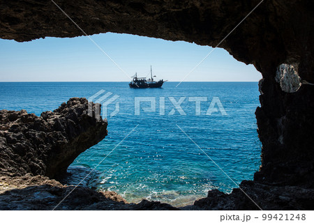 Pirate ship sailing in the sea. View from a cave 99421248