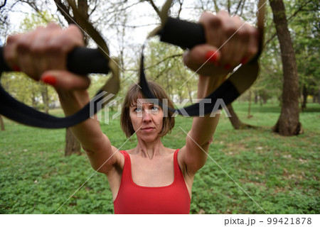 Woman doing arms biceps curl training with trx fitness straps Woman doing arms biceps curl training with trx fitness straps 99421878