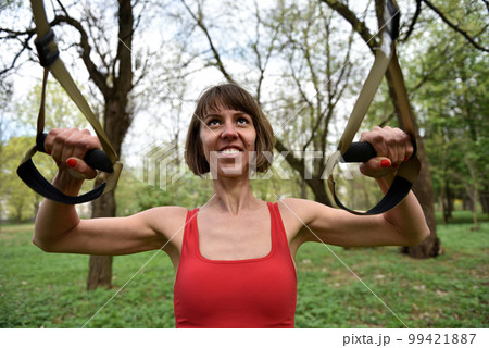 Woman doing arms biceps curl training with trx fitness straps Woman doing arms biceps curl training with trx fitness straps 99421887