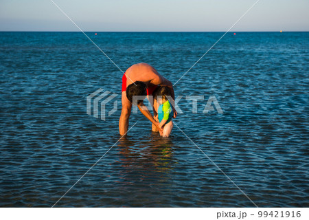 Father and daughter playing together in the sea water Father and daughter playing together in the sea water 99421916