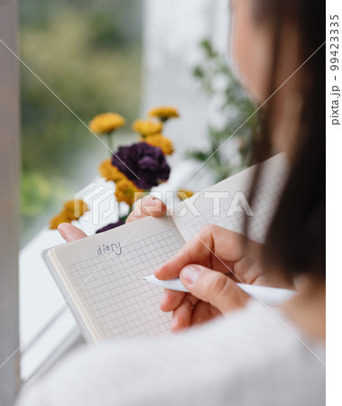 view from back, woman writes notes in notebook or diary. mental health care, psychotherapy view from back, woman writes notes in notebook or diary. mental health care, psychotherapy 99423335