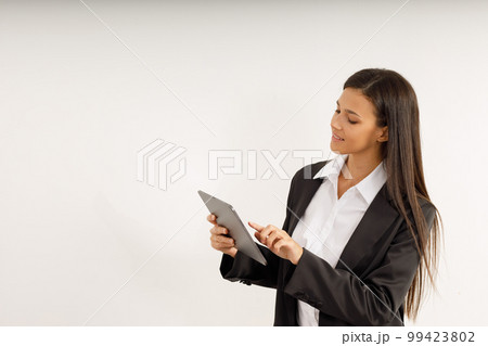 Portrait of successful business woman with tablet in her hands, dressed in white shirt and black jacket on isolated white background. Studio shot of attractive brunette girl 99423802