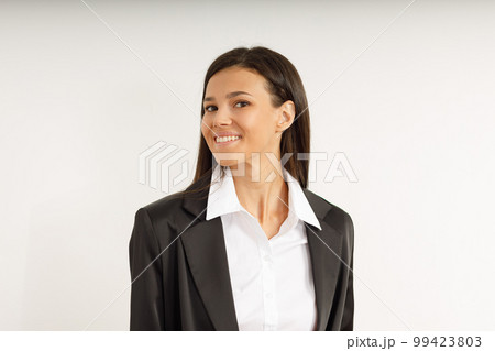 Portrait of happy smiling brunette girl dressed in white shirt and black jacket. Beautiful model on isolated white background. Studio shot of young attractive woman in business suit. Portrait of happy smiling brunette girl dressed in white shirt and black jacket. Beautiful model on isolated white background. Studio shot of young attractive woman in business suit. 99423803