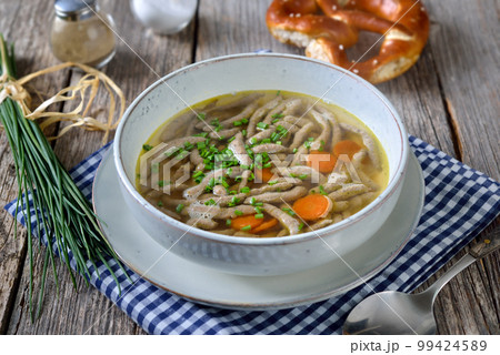 Bavarian, Swabian and Austrian dish - liver spaetzle  in a beef soup served with a crispy pretzel 99424589