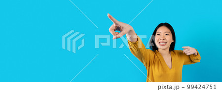 Excited asian woman pointing at copy space for advertisement, web-banner 99424751