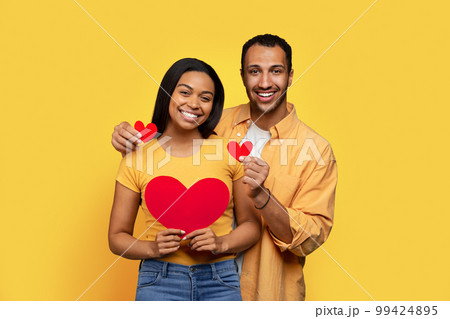 Smiling young african american lady and boyfriend holding hearts in hands, enjoy relationships 99424895
