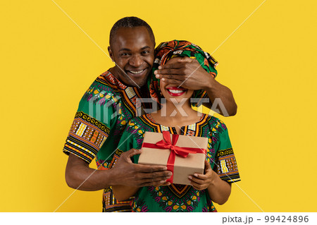 Loving black man make surprise for wife, wearing african outfits Loving black man make surprise for wife, wearing african outfits 99424896