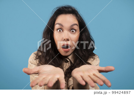 Shocked millennial european lady student with open mouth show hands to camera Shocked millennial european lady student with open mouth show hands to camera 99424897