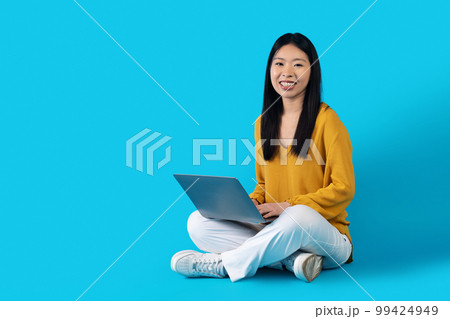 Cute chinese lady student using laptop on blue 99424949