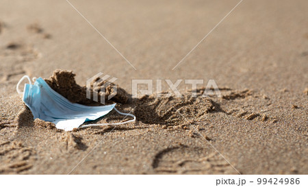 Used surgical mask thrown on seashore of beach, medical waste, garbage, trash on sea water, panorama with free space 99424986