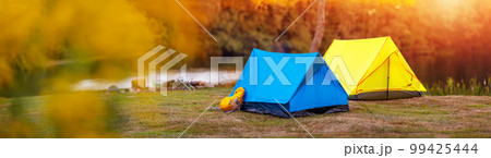 Panoramic view of the campground with colourful tents near the lake in wilderness park. 99425444