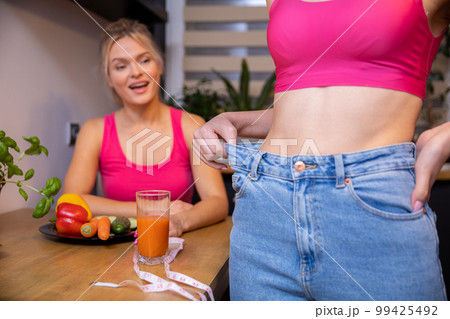 Two women in sporty pink tops at a health food table 99425492