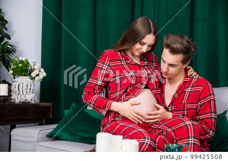 girl sits on the lap of her boyfriend, who touches her pregnant belly 99425508