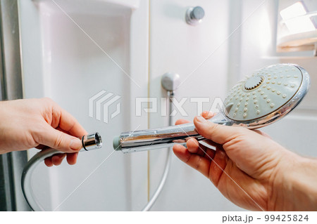men's hands screw the shower head onto a new hose. men's hands screw the shower head onto a new hose. 99425824