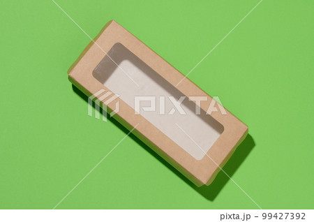Rectangular cardboard box with a transparent plastic lid on a green background, top view Rectangular cardboard box with a transparent plastic lid on a green background, top view 99427392