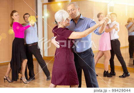 Elderly pair practicing ballroom dance in dance studio Elderly pair practicing ballroom dance in dance studio 99429044