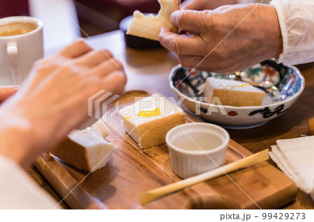 トーストを分け合って食べるシニア夫婦 99429273