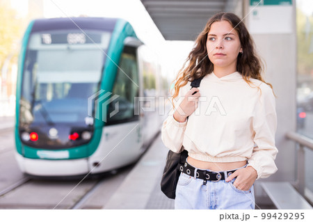 Woman waiting for tram on platform of public transport station Woman waiting for tram on platform of public transport station 99429295