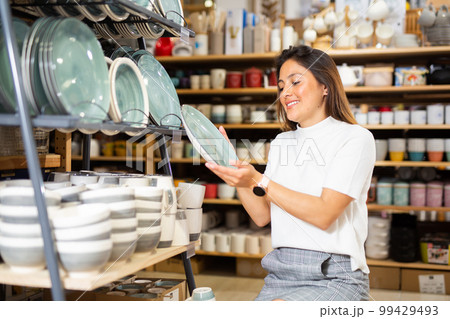 Woman selecting crockery in tableware store 99429493