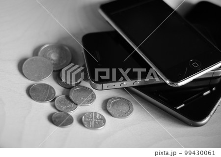積まれたスマートフォンと海外のお金　モノクロ 99430061