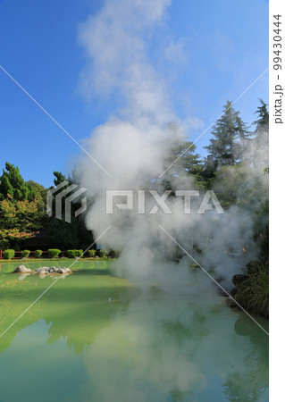 別府白池地獄の湯けむりが上がる青白色の温泉の景色 99430444