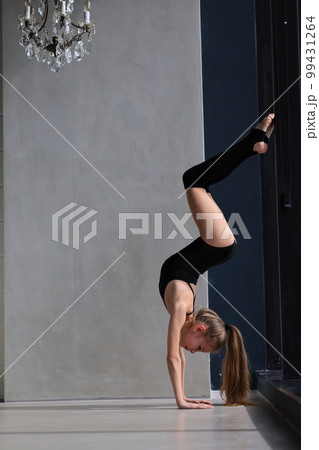 slim artistic teenage girl in black leotard training and leggings is training. rhythmic gymnastic exercise, children's professional sports 99431264
