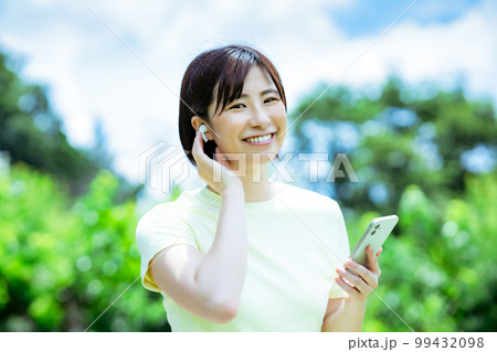 新緑の中で音楽を聴く女性 99432098