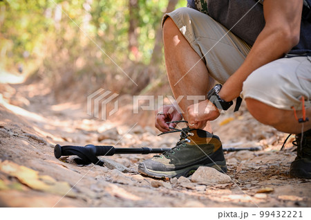 Cropped image of an active Asian man with trekking gear tying his shoelaces 99432221