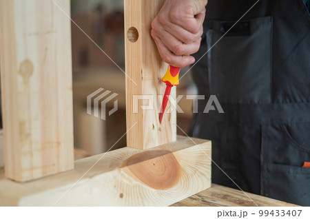 Caucasian man assembles the table with a screwdriver. Close-up of a carpenter's hands. 99433407