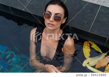 Beautiful european woman in black swimsuit posing outside at villa in swimming pool, on vacation, perfect shape, good body, tanned, fit, wearing trendy brown sunglasses Beautiful european woman in black swimsuit posing outside at villa in swimming pool, on vacation, perfect shape, good body, tanned, fit, wearing trendy brown sunglasses 99433890