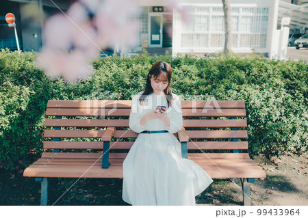 公園でスマホを触っている若い女性の写真 公園でスマホを触っている若い女性の写真 99433964