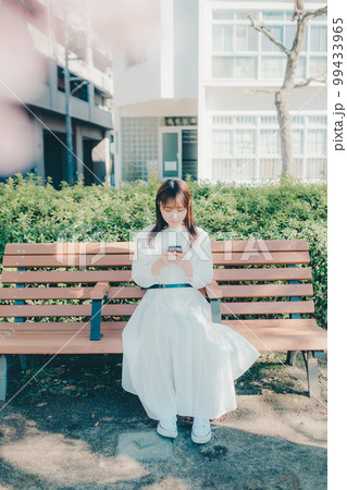 公園でスマホを触っている若い女性の写真 公園でスマホを触っている若い女性の写真 99433965