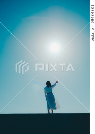 浜辺に佇む若い女性の写真 99434331