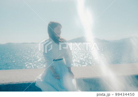 浜辺に佇む若い女性の写真 99434450