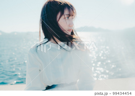 浜辺に佇む若い女性の写真 99434454
