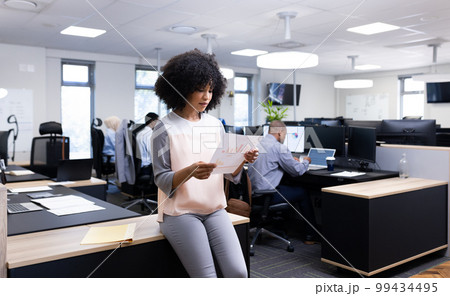 Happy biracial businesswoman with document working in office 99434495