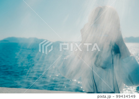 浜辺に佇むカメラを持った若い女性の写真 99434549