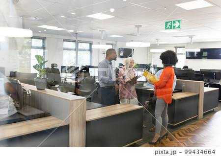 Happy diverse female and male businesspeople talking and working in office Happy diverse female and male businesspeople talking and working in office 99434664