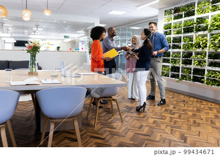 Happy diverse female and male businesspeople talking and working in office Happy diverse female and male businesspeople talking and working in office 99434671