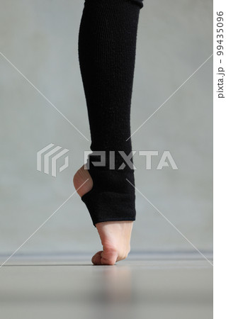 Sports legs close up. Training, element of gymnastics, performs exercises on a grey background. Sports motivation, stretching, physical education 99435096